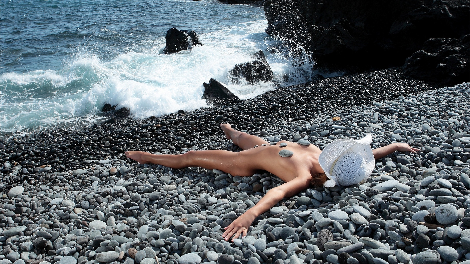 Молодая модель позирует обнаженной на каменистом берегу порно фото