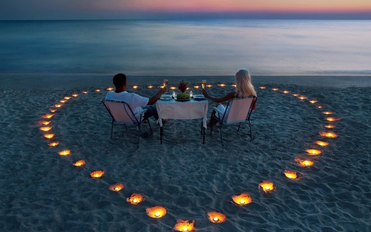 мужчина и женщина пьют вино на берегу, свечи на песке в форме сердца, man and woman drinking wine on the shore, candles on the sand in the shape of a heart