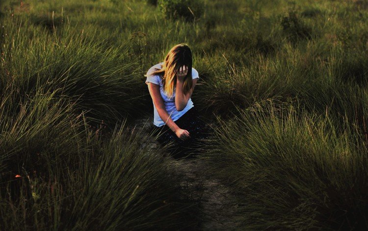 Девушка сидит среди высокой травы
