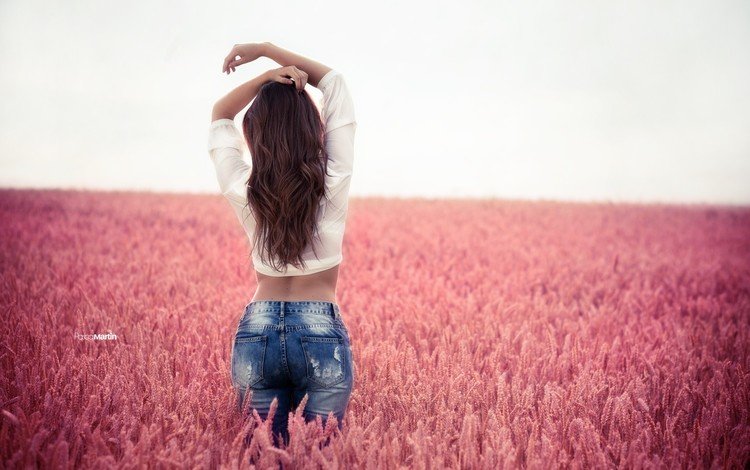 Девушка стоит спиной в поле розовых цветов