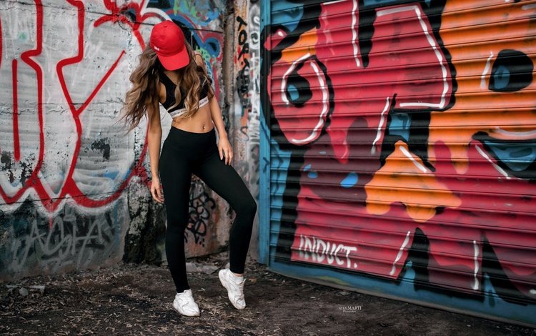 Спортивная девушка возле стены графити