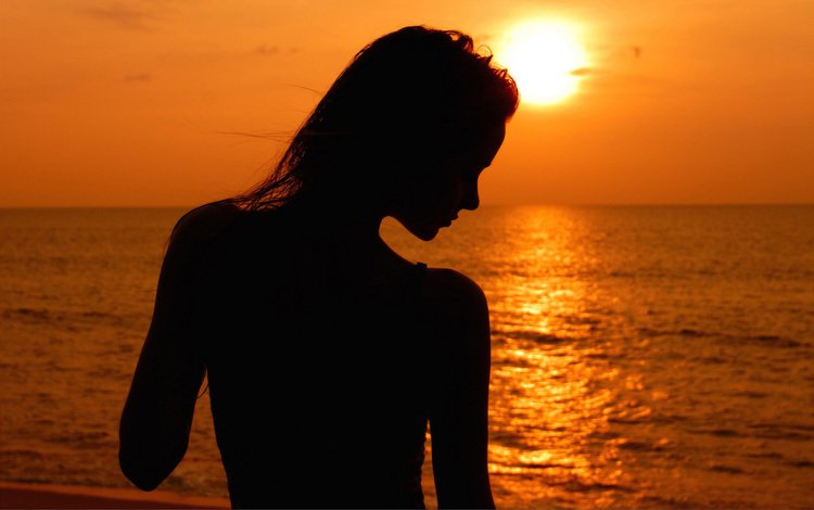 Силуэт девушки во время заката на море