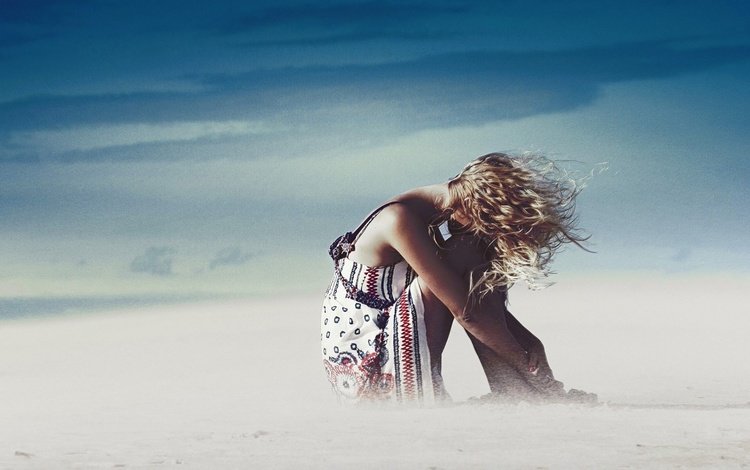 Девушка сидит на песке